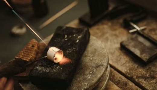 Jewelry work being heated at a jeweler's bench